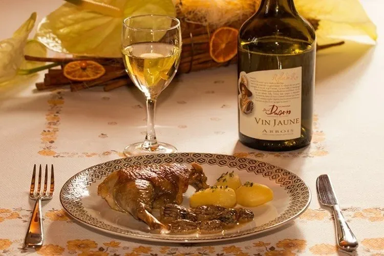 Plated Bresse chicken leg with morel cream sauce, potatoes, and a glass of Vin Jaune